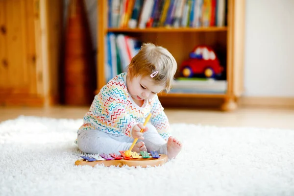 Niña jugando con juguetes educativos de música de madera en casa o en el vivero. Niño pequeño con xilofón de madera de colores. Niño solitario durante la cuarentena pandémica del virus corona. —  Fotos de Stock