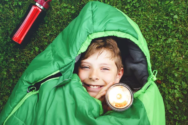 Niño preadolescente de la escuela en el campamento saco de dormir. Actividad al aire libre con niños en verano. Campamento de diversión y aventura, vacaciones en familia y amigos o viaje de fin de semana. Retrato de niño con linterna. —  Fotos de Stock