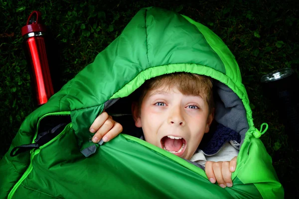 Preteen school kid boy in sleeping bag camping. Outdoors activity with children in summer. Fun and adventure camp, family and friends vacations or weekend trip. Portrait of child with flashlight. — Stock Photo, Image