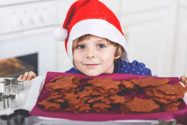 Kreş çocuğu zencefilli kurabiye pişiriyor. Xmas süveter giyen mutlu, yeni yürümeye başlayan çocuk. Mutfak Noel için dekore edildi. Noel aile aktivitesi