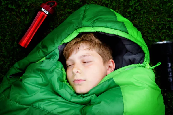 小学生在睡袋露营。夏天与孩子们一起在户外活动。有趣和冒险营，家人和朋友度假或周末旅行。手电筒的儿童肖像. — 图库照片