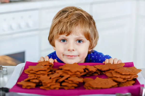 Kleine Vorschulkinder backen Lebkuchen. Glückliches aktives Kleinkind im Weihnachtspullover. Weihnachtlich dekorierte Küche. Familienaktivitäten zu Weihnachten — Stockfoto