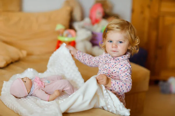 Gadis balita kecil yang manis bermain dengan boneka. Bayi yang sehat bersenang-senang dengan permainan peran, bermain sebagai ibu di rumah atau pembibitan. Putri aktif dengan mainan. — Stok Foto
