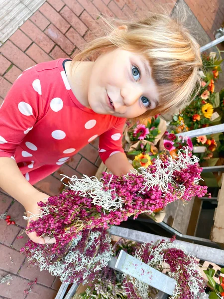 Dziewczynka kupuje jesienny wieniec w sklepie z dekoracjami. Cute szczęśliwy dziecko grać z dekoracji jesiennej. Dzieci i jesień, uroczystość dziękczynienia. — Zdjęcie stockowe