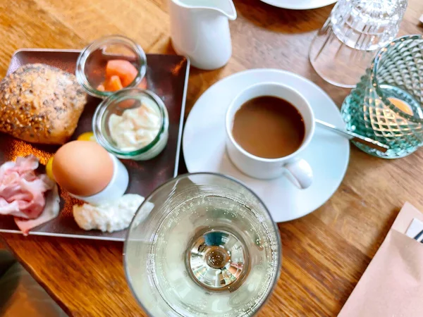 Tafel gedekt voor ontbijt buiten in de zomer met diverse jam, brood, koffie, croissants, eieren, spek muesli en sinaasappelsap — Stockfoto