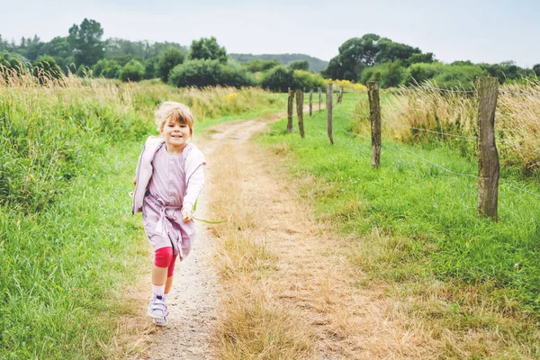 Šťastné malé batolátko běhající v přírodě, letní procházka po polích, venku. Vtipná dětská jízda ve školce se baví běháním, chůzí, skákáním v letní den. Aktivní rodinný volný čas v létě. — Stock fotografie