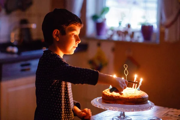 Adorable niño rubio feliz celebrando su cumpleaños. Niño soplando velas en pastel horneado casero, en el interior. Fiesta de cumpleaños para los niños de la escuela, celebración familiar, fuegos artificiales —  Fotos de Stock