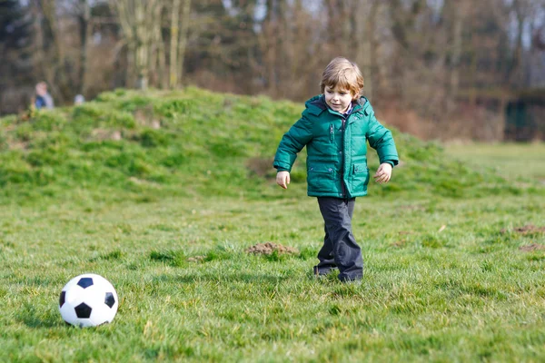 Menino jogando futebol ou futebol em dia frio — Fotografia de Stock