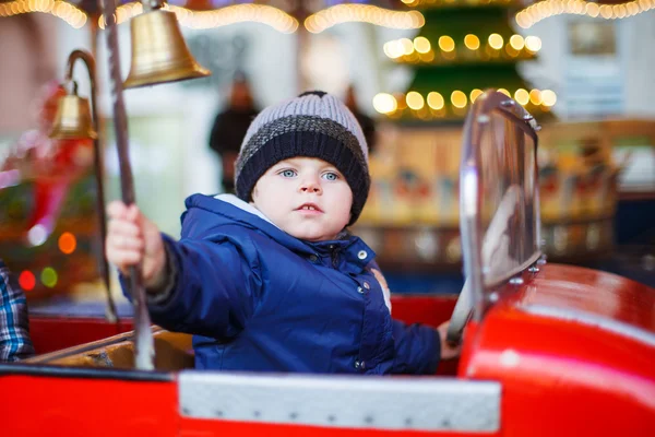 Adorable niño pequeño en un carrusel en la feria de Navidad o marca — Foto de Stock
