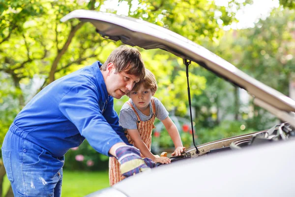 Young father teaching his little son to change motor oil in fami — Stock Photo, Image