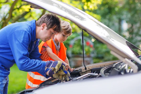 Junger Vater bringt seinem kleinen Sohn bei, Motoröl in Hungersnöten zu reparieren — Stockfoto