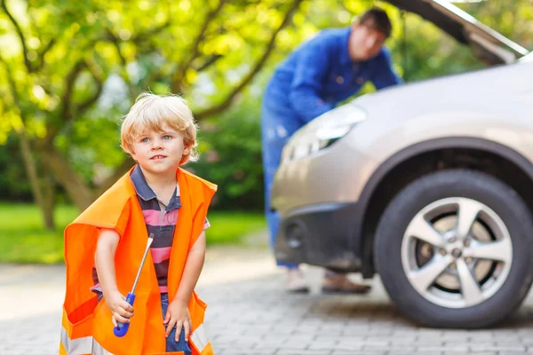 Joven padre enseñando a su pequeño hijo a reparar aceite de motor en fami — Foto de Stock