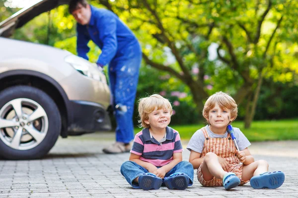 Zwei kleine Geschwister in orangefarbener Warnweste beim Vater — Stockfoto