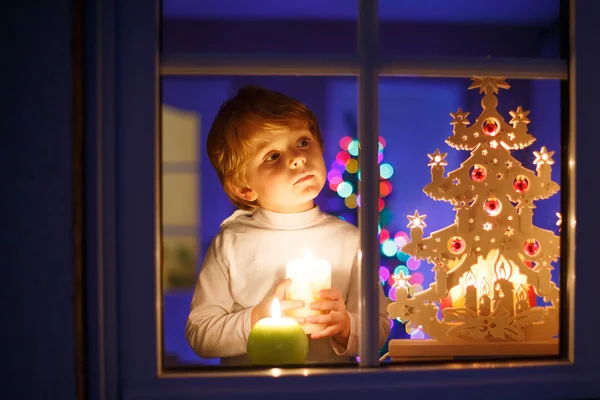 Маленький мальчик, стоящий у окна на Рождество — стоковое фото
