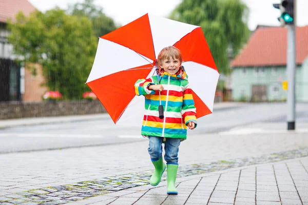 Schönes Kind mit gelbem Regenschirm und farbenfroher Jacke draußen — Stockfoto