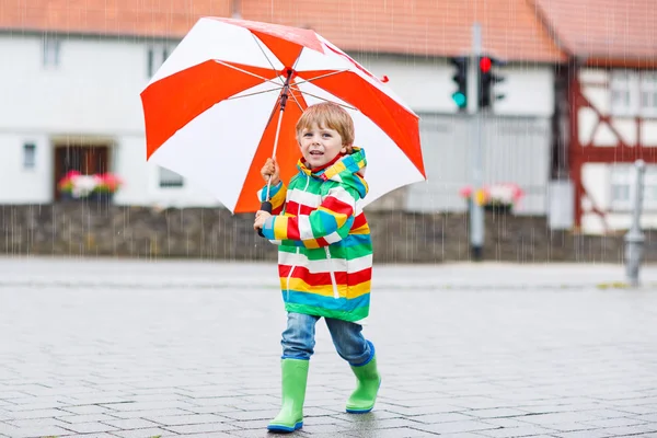 Bellissimo bambino con ombrello giallo e giacca colorata all'aperto — Foto Stock