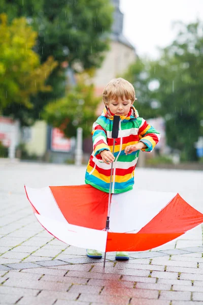 Niño feliz con paraguas amarillo y chaqueta colorida outdoo —  Fotos de Stock