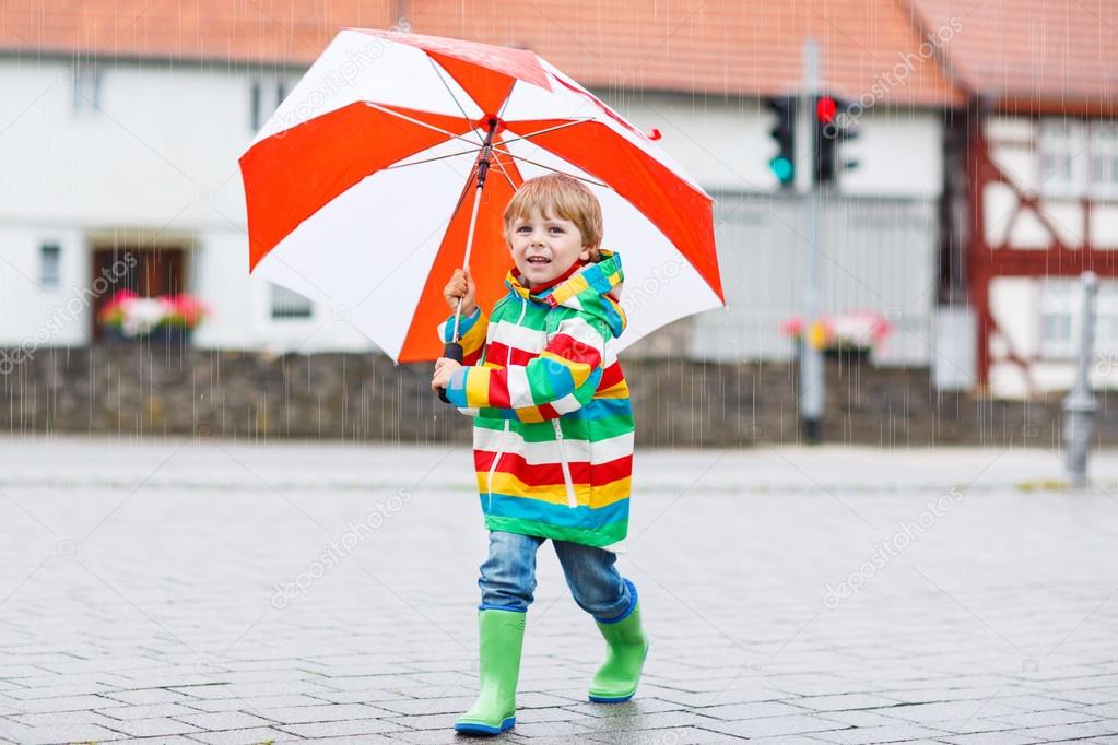 Beautiful child with yellow umbrella and colorful jacket outdoor