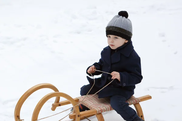 Un niño encantador en el antiguo trineo en el día de invierno — Foto de Stock