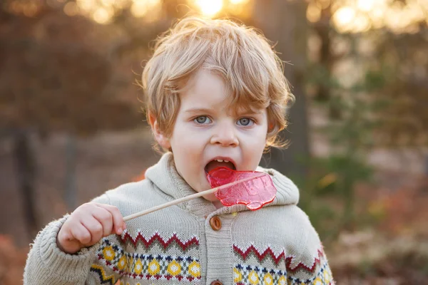 Menino pequeno caucasiano de dois anos comendo doces grandes — Fotografia de Stock