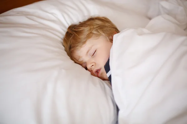 Pequeño chico rubio durmiendo en su cama — Foto de Stock