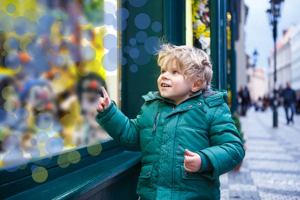 Очаровательный маленький мальчик, смотрящий в окно на рождественское деко — стоковое фото