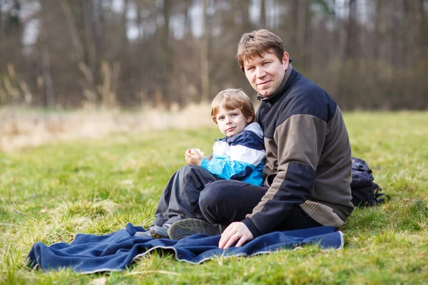 Mladý otec a malý syn s piknik a zábavy poblíž lesa la — Stock fotografie