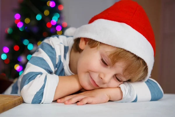 Little boy in santa hat with christmas tree and lights — Stock Photo, Image
