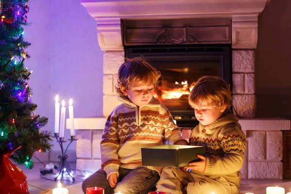 Due bambini piccoli seduti accanto a un camino a casa a Natale — Foto Stock