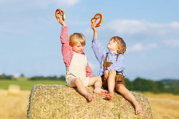 Deux petits enfants assis sur une pile de foin et mangeant du bretzel — Photo