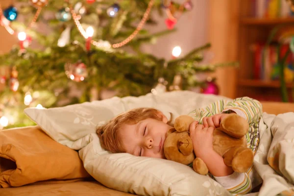 Pequeño niño rubio lindo durmiendo bajo el árbol de Navidad — Foto de Stock