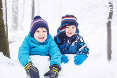 mutlu bir aile: iki küçük ikiz erkek eğleniyor kar winte içinde