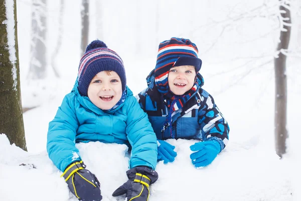 Szczęśliwa rodzina: dwóch chłopców twin zabawy z śniegu w garniturów źim — Zdjęcie stockowe