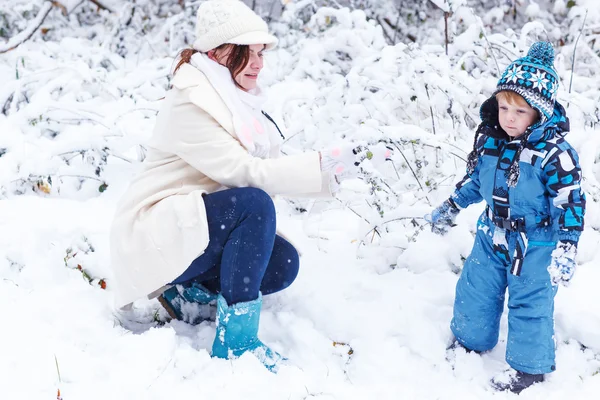 Poco niño preescolar y su madre jugando con la primera nieve en p —  Fotos de Stock