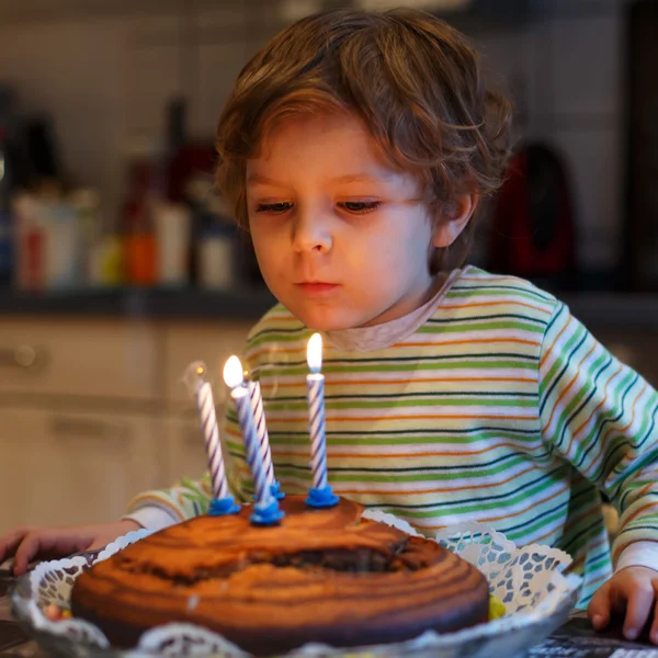 Adorable niño de cuatro años celebrando su cumpleaños y soplando —  Fotos de Stock