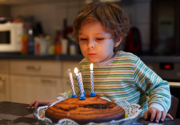 Adorable four year old boy celebrating his birthday and blowing — Stock Photo, Image