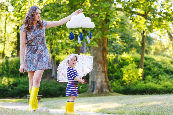 Mother and little adorable child in yellow rubber boots — Stock Photo, Image