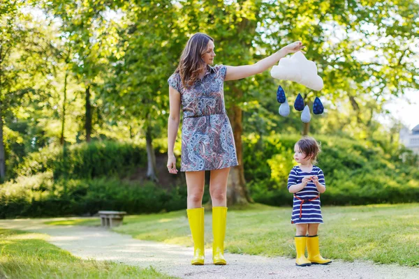 Mother and little adorable child in yellow rubber boots — Stock Photo, Image