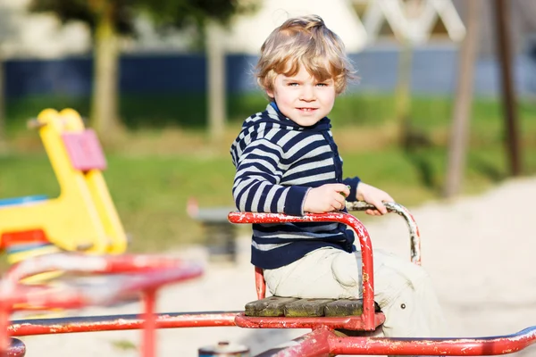 Little toddler boy having fun on old carousel on outdoor playgro — Stock Photo, Image