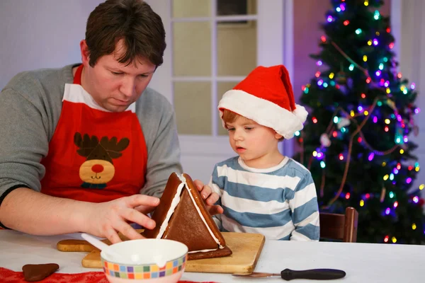 Padre e hijo pequeño preparando una casa de galletas de jengibre — Foto de Stock