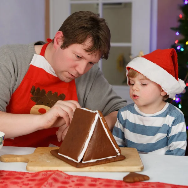 Vater und kleiner Sohn beim Zubereiten eines Lebkuchenhauses — Stockfoto