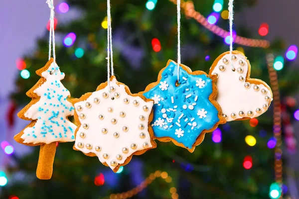 Peperkoek cookies opknoping met kerstboom op achtergrond. — Stockfoto