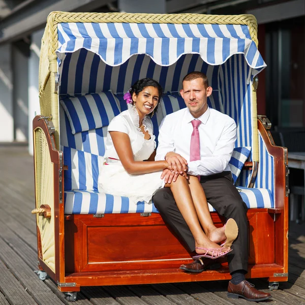 Beautiful indian bride and caucasian groom, in beach chair. — Stock Photo, Image