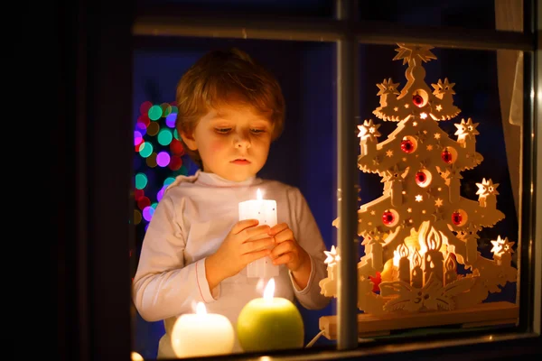 Kleiner Junge steht zur Weihnachtszeit am Fenster — Stockfoto