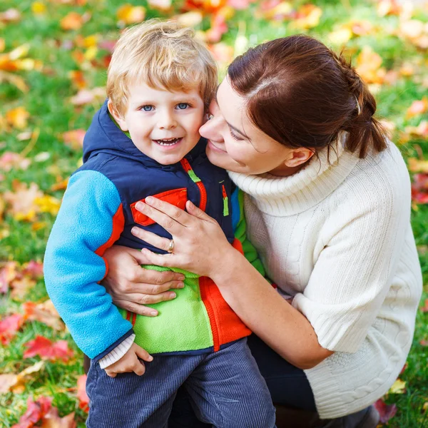 Young mum and her little kid son hugging together in autumn park — Stock Photo, Image