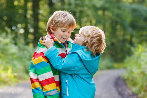 Dva malí kluci sourozence v barevné pláštěnky a boty chůze — Stock fotografie