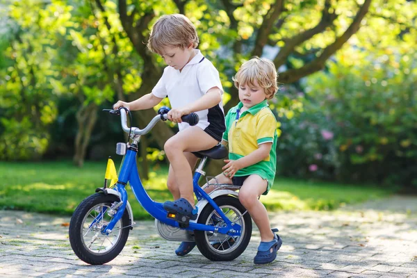 Two happy little sibling kids having fun together on one bicycle — Stock Photo, Image