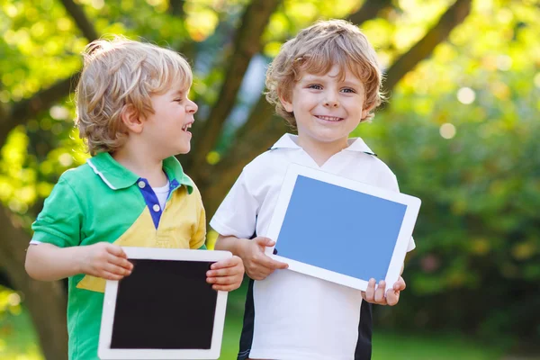 Dos niños felices hermanitos sosteniendo la tableta PC, al aire libre —  Fotos de Stock