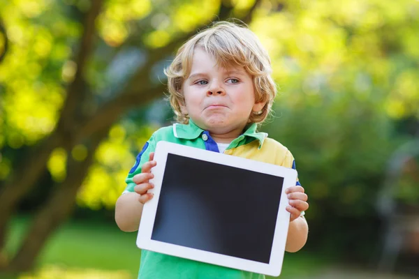 Bedårande glad liten unge pojke håller TabletPC, utomhus — Stockfoto