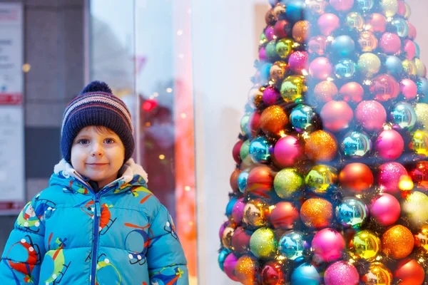 Adorable little boy looking through the window at Christmas deco — Stock Photo, Image